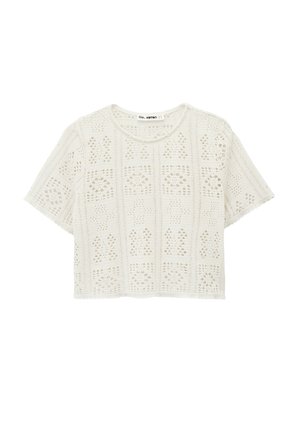 Wit kort mouwtjes crochet gebreid cropped topje met een geometrisch opengewerkt patroon en een ronde halslijn.