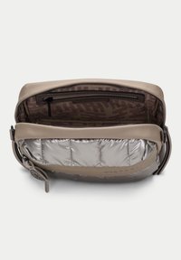 Beige koženková taška se stříbrnou prošívanou podšívkou. Zapínání na zip, vnitřní kapsa a viditelné označení značky. Hladký vnější povrch.