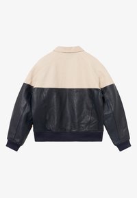 Læderjakke i creme og marineblå, med en glat tekstur og en krave. Har ribbede manchetter og kant, der viser et farveblokdesign.
