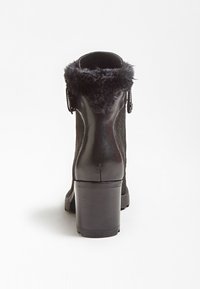 Bottines noires avec un col en fausse fourrure, des panneaux latéraux texturés, un bout arrondi et un talon bloc de hauteur moyenne. Matériau lisse avec des détails de couture.