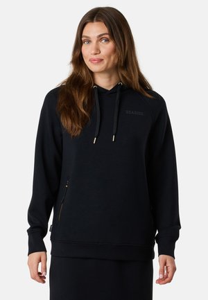 Zwarte capuchontrui van zacht materiaal, met een voorzak, koordjes en een logo op de borst. Eenvoudig, ontspannen ontwerp.