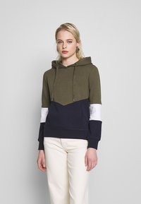 Sweatshirt com capuz em verde oliva, azul-marinho e branco. Material em mistura de algodão com um design de chevron. Apresenta cordões e punhos canelados.