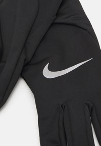 Black fabric gloves featuring a textured design and a prominent reflective silver Nike swoosh logo on the back.