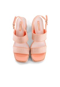 Sandalias de cuña de color durazno con dos correas texturizadas, una puntera suave y brillante, y una hebilla ajustable en el tobillo.