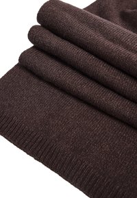 Tissu tricoté marron plié soigneusement, mettant en valeur un tissage doux et texturé avec des bords côtelés. Le matériau semble chaud et douillet.