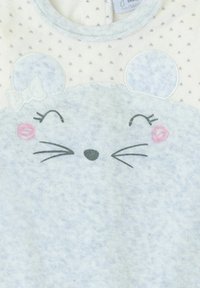 Body suave azul para bebé con la cara sonriente de un ratón, mejillas rosadas, bigotes y un lazo en una oreja sobre un fondo claro con pequeños patrones de corazones.