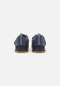 Navy athletic shoes with a smooth textile upper, grey-striped accents, dual pull tabs, and a gum rubber outsole.