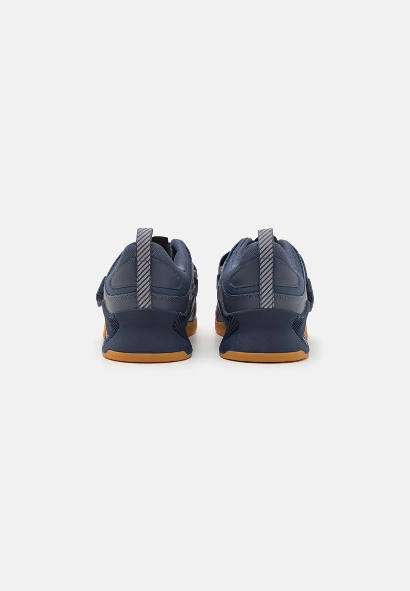 Marineblaue Sportschuhe mit einem glatten Textil-Obermaterial, grauen Streifenakzenten, doppelten Zuglaschen und einer Sohle aus Gummirubber.