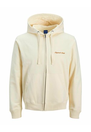 Zip-up hooded sweatshirt in cream, made of soft fabric. Features side pockets, ribbed cuffs, and embroidered logo on chest.