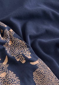 Tessuto blu navy con un motivo testurizzato in oro di animali stilizzati. Texture morbida con pieghe drappeggiate, che enfatizzano la chiarezza del design.