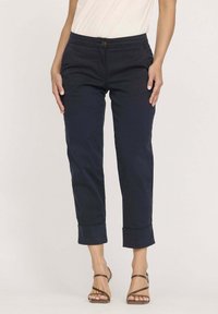 Chinos en coton navy avec une coupe slim, poignets retroussés, poches avant et fermeture à bouton à la taille. Texture lisse et design ajusté.