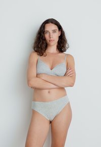 Grå bomulls-bh med V-hals design og tynne stropper, kombinert med matchende grå bomulls-bikini truser. Enkel, jevn tekstur.