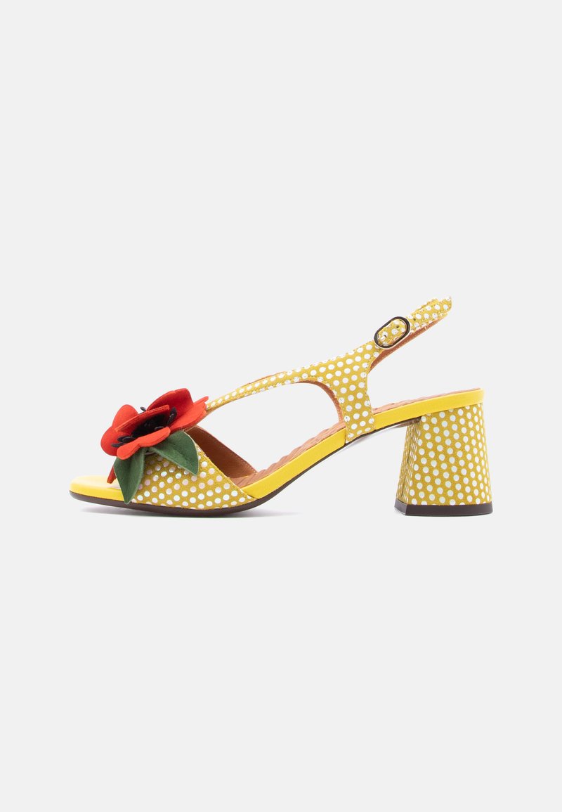 Sandale slingback jaune à pois avec un accent floral, talon bloc bas et design à bout ouvert. Comprend une bride réglable et une semelle intérieure texturée.