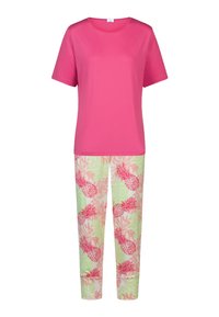 Lyserød t-shirt med korte ærmer kombineret med lysegrønne bukser med et tropisk ananasprint i pink og rød mod en bladmønsterbaggrund.