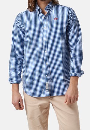 Camisa abotonada de cuadros azules y blancos con mangas largas, diseñada con un collar tipo button-down y un acento de logo rojo en el pecho.