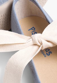 Hellblaues Stoffschuh mit einer beigefarbenen Leinenschnürung. Verfügt über eine strukturierte Sohle und ein bedrucktes Logo in Blau auf einer naturfarbenen Fußbett.