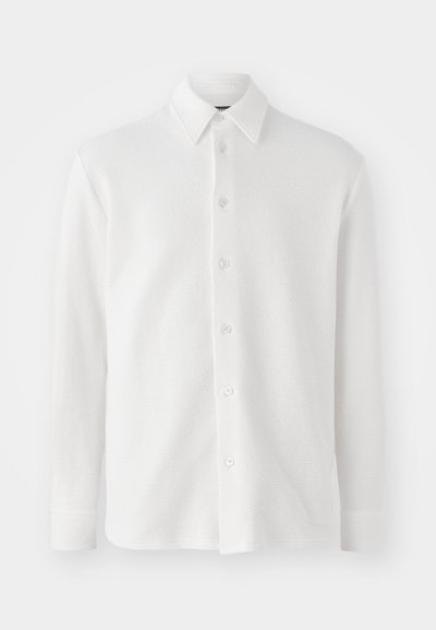 Witte overhemdd met structuurstof. Voorzien van een klassieke kraag, lange mouwen en zes knopen aan de voorkant. Zacht, lichtgewicht ontwerp.
