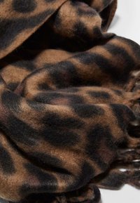 Šal s uzorkom leoparda u nijansama smeđe i crne boje, izrađen od mekanog materijala. Ima uvrnute ivice i teksturirani završetak.