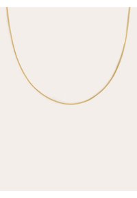 Collier en métal doré, fin et lisse, avec un léger éclat. Présente un design délicat et épuré, adapté à être porté en superposition ou en solo.