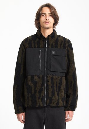 Chaqueta de forro polar con un patrón de camuflaje negro y oliva, con un panel frontal negro, bolsillos con cremallera y un cuello alto.