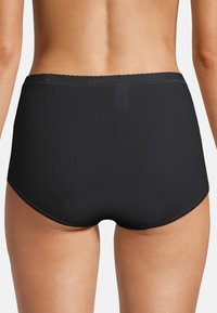 Slips neri in cotone a vita alta con una texture liscia, un elastico ondulato in vita e nessuna cucitura visibile per una vestibilità elegante.