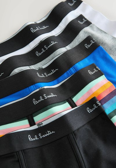 Sept paires de boxers pour hommes en blanc, gris, bleu, rayé et noir, chacune avec une ceinture noire marquée "Paul Smith".