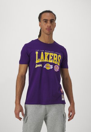 Maglietta viola con la scritta "LAKERS" in bold giallo, con loghi della squadra e una toppa vicino all'orlo. Realizzata in cotone, design a maniche corte.