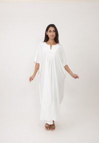 Kaftan blanc ample avec un col en V, des manches courtes et des détails froncés à l'avant. Tissu léger et lisse avec une coupe fluide.