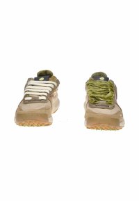 Zapatillas deportivas color canela con texturas variadas: la izquierda tiene cordones lisos, la derecha presenta un material plisado verde. Suelas de goma con tracción.