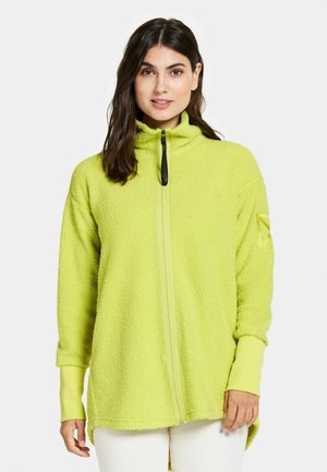 Fleece takki kirkkaassa limevihreässä, jossa on korkea kaulus, täysi etuvetoketju ja pitkät hihat, joissa on hihansuihin tehdyt korostukset. Pehmeä, teksturoitu kangas.