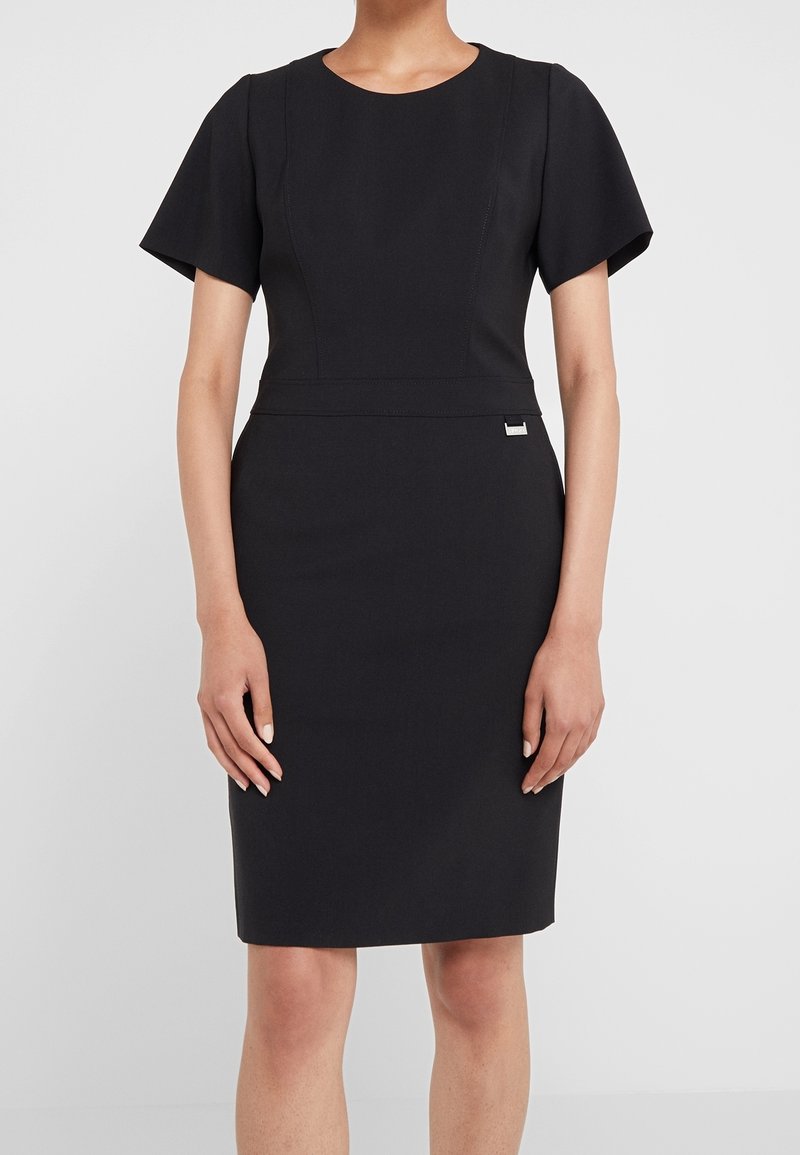 Robe ajustée noire avec manches courtes volantées, encolure ronde et coutures accentuées. Présente un petit détail logo à la taille. Texture lisse.