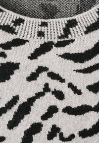 Sweter robiony na drutach, z jasnoszarym tłem i wyrazistym czarnym wzorem zwierzęcym. Teksturowana tkanina ma ściągaczowy dekolt i miękkie wykończenie.