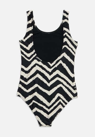Maillot de bain une pièce à motif chevrons noir et blanc avec un profond décolleté en V et des larges bretelles.