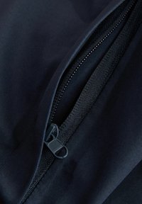 Tejido azul marino oscuro con una textura suave que presenta un detalle de cremallera y costuras negras contrastantes a lo largo de la costura.