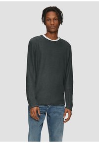 Donkergrijze langekoon t-shirt in een relaxte pasvorm, met een witte ronde halsafwerking. Zachte stof met een gladde textuur. Draag het met blauwe spijkerbroeken.