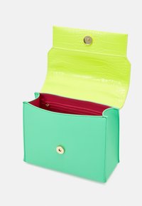 Green leather handbag with a textured yellow flap. Features a gold snap closure and a contrasting red interior with a zip pocket.
