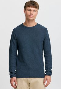 Granatowy sweter dzianinowy z długimi rękawami i okrągłym dekoltem. Posiada teksturowany wzór oraz ściągacze na mankietach i u dołu.