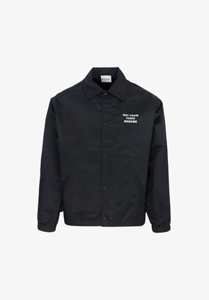 Giacca nera in tessuto liscio, con chiusura a bottoni sul davanti, colletto e testo stampato bianco: "NON DI PARIGI MADAME." Maniche con polsini elasticizzati.