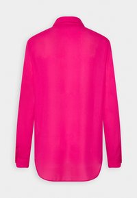 Blouse rose vif à manches longues avec col classique, poignets boutonnés et ourlet arrondi vue de dos.