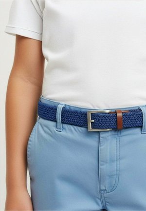 Enfant portant un pantalon bleu clair et une chemise blanche avec une ceinture tissée bleu foncé texturée, attachée par une boucle argentée.