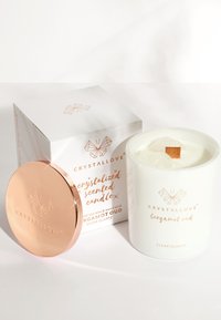 Candela bianca con stoppino in legno in un contenitore in ceramica, caratterizzata da pezzi di quarzo chiaro, con coperchio in oro rosa. Accompagnata da una scatola decorata.
