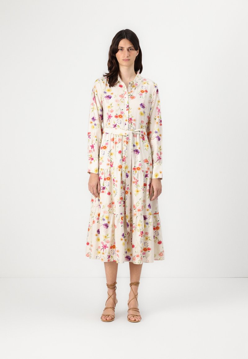 Rochie midi florală în crem, cu mâneci lungi, croială dreaptă, închidere cu nasturi în față, talie strânsă și fustă cu volane, decorată cu flori multicolore.