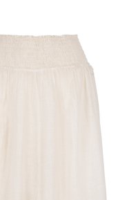 Lichtbeige maxi-jurk met een smocktailleband, gemaakt van zachte, lichte stof, met een gladde textuur en een vloeiende design.