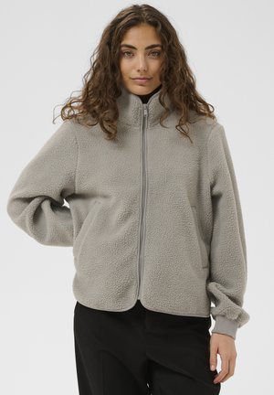 Hellgraue Fleecejacke mit hohem Kragen, Reißverschluss vorne, zwei Seitentaschen und gerippten Bündchen; weiche Textur, bequeme Passform.