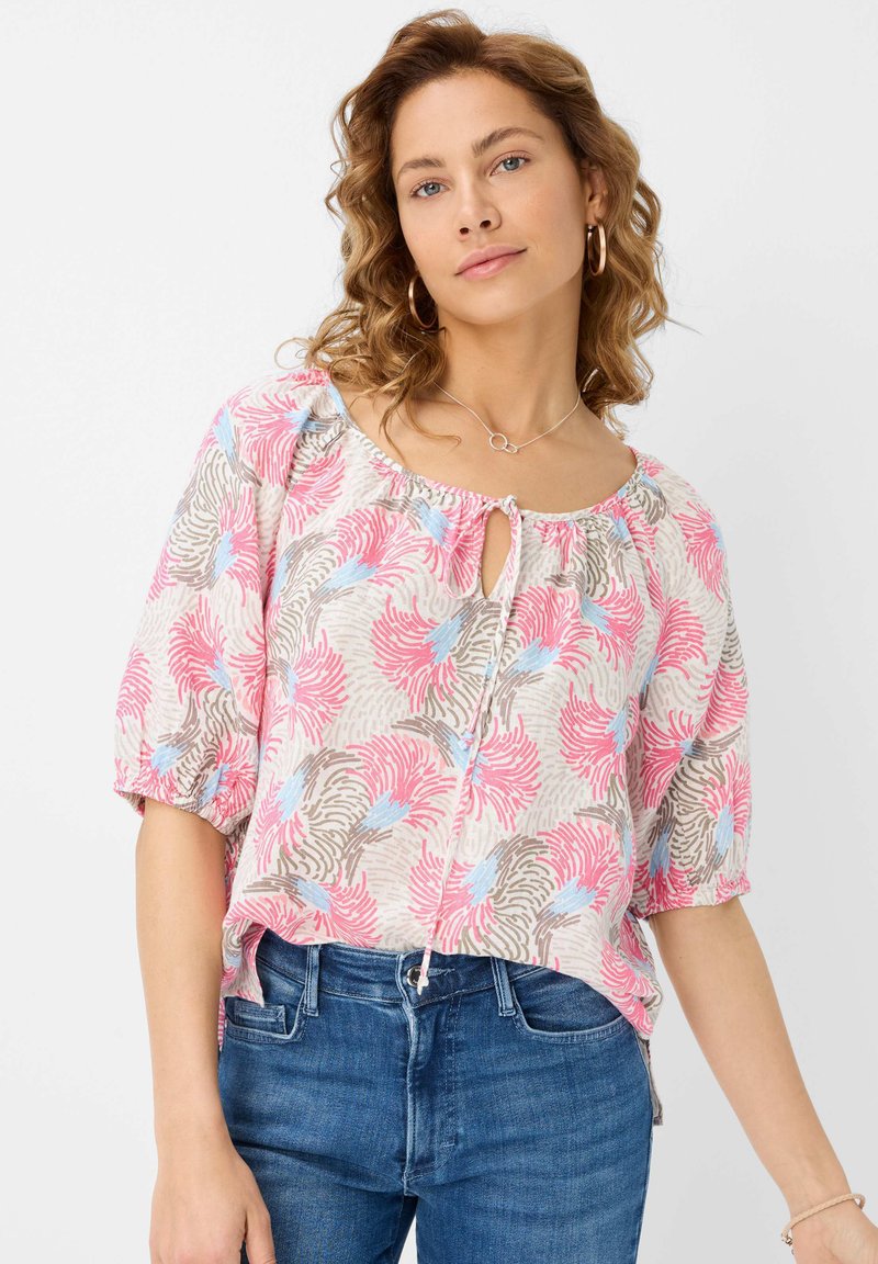 Korte mouwen blouse van lichte stof met een bloemenpatroon in roze, blauw en bruin. Sleutelgat-halslijn met striksluiting. Relaxte pasvorm, net iets cropped.