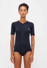 Īsām piedurknēm melna rash guard krekls ar priekšējo rāvējslēdzēju, apaļu kakla izgriezumu un logo uz kreisās krūtis. Gluda tekstūra, pieguļoša forma.