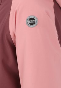 Tissu de veste rose clair avec une finition texturée, comportant un écusson circulaire gris "ZIGZAG" sur la manche gauche, contrastant avec un panneau latéral marron.