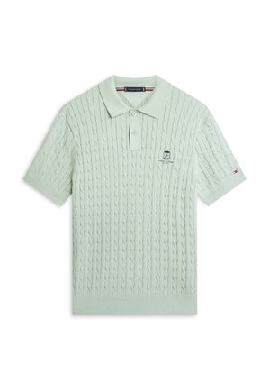 Hellgrünes Polohemd mit kurzen Ärmeln und Zopfmuster, Zwei-Knopf-Leiste, besticktem Tommy Hilfiger-Logo auf der Brust und kleinem Flaggen-Detail am Ärmel.