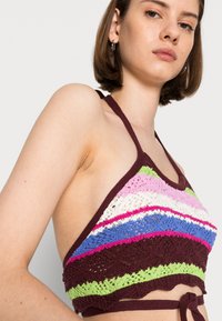 Top de crochê tipo halter em riscas multicoloridas: rosa vibrante, verde, azul e branco com um acabamento em castanho escuro e um fecho com laço nas costas.