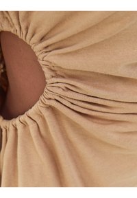 Jasnobrązowa tkanina o marszczonej teksturze, z okrągłym wycięciem. Miękki, elastyczny materiał z ciasno marszczonymi detalami.